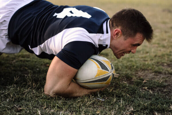 Strong rugby player with ball on ground during the game. Rugby player with possession of the ball in the match.