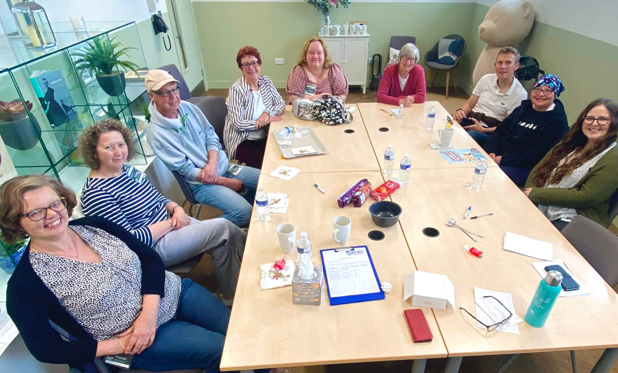 Small group of people sitting around a table in a meeting room, smiling