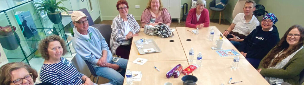 Small group of people sitting around a table in a meeting room, smiling