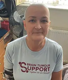 Woman after a Brave the Shave challenge with shaven head and wearing Brain Tumour Support t-shirt