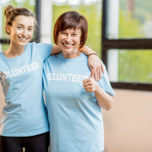 Two women wearing pale blue tee shirts saying 'volunteer'