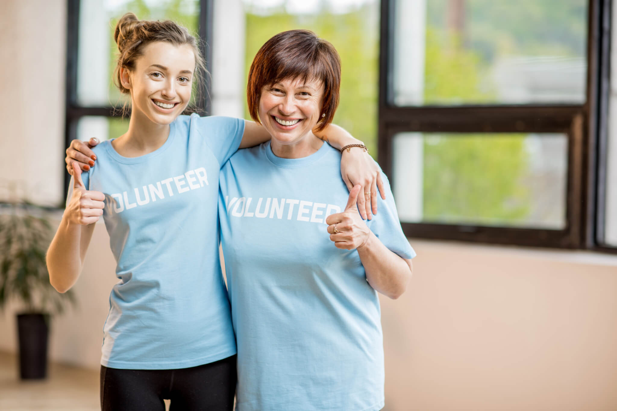 Two women wearing pale blue tee shirts saying 'volunteer'