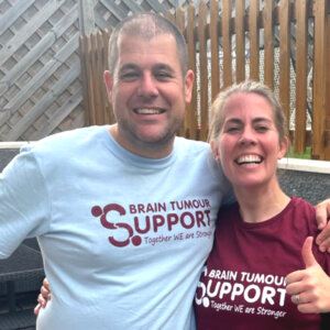 Man and woman in Brain Tumour Support t-shirts smiling and giving thumbs up