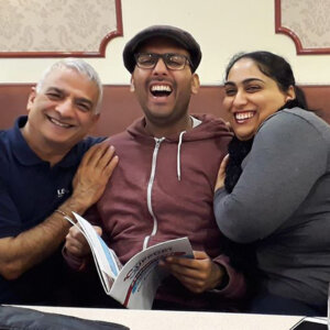 Man in cap in centre of image surrounded by family members, all smiling