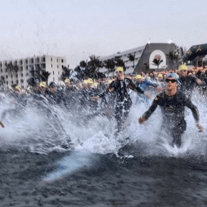 Group of people in wetsuits running into the sea