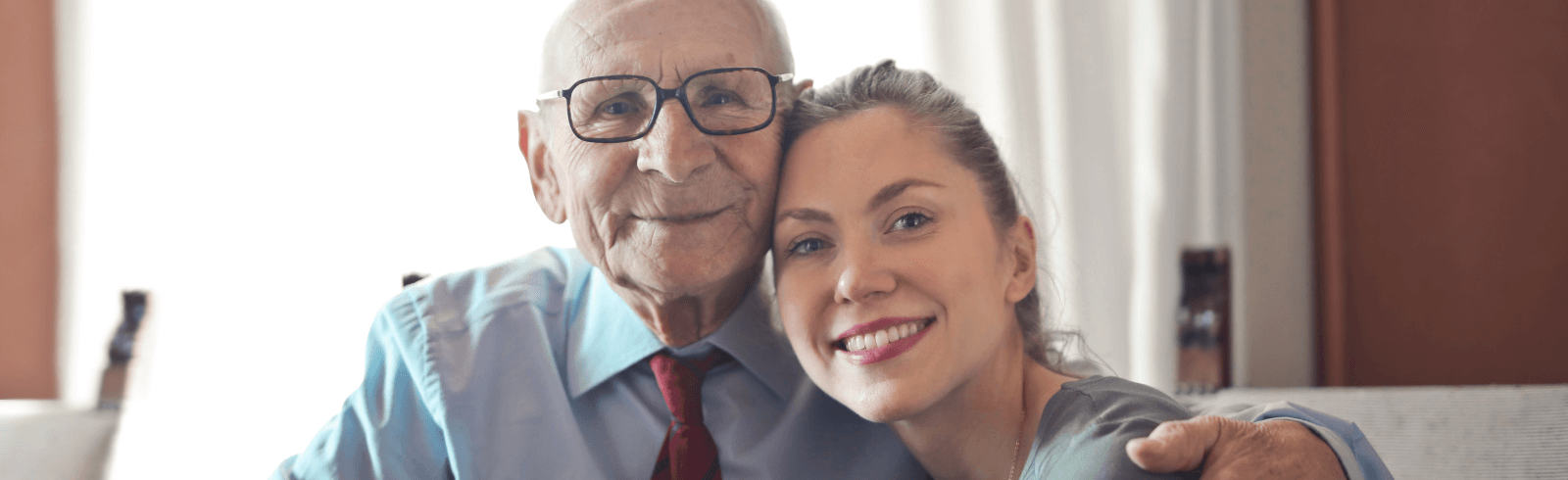 Grandfather-with-arm-round-granddaughter-looking-and-smiling-at-camera