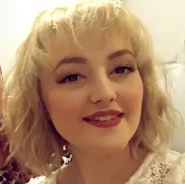 Pretty girl with shoulder-length wavy blonde hair looking and smiling at the camera
