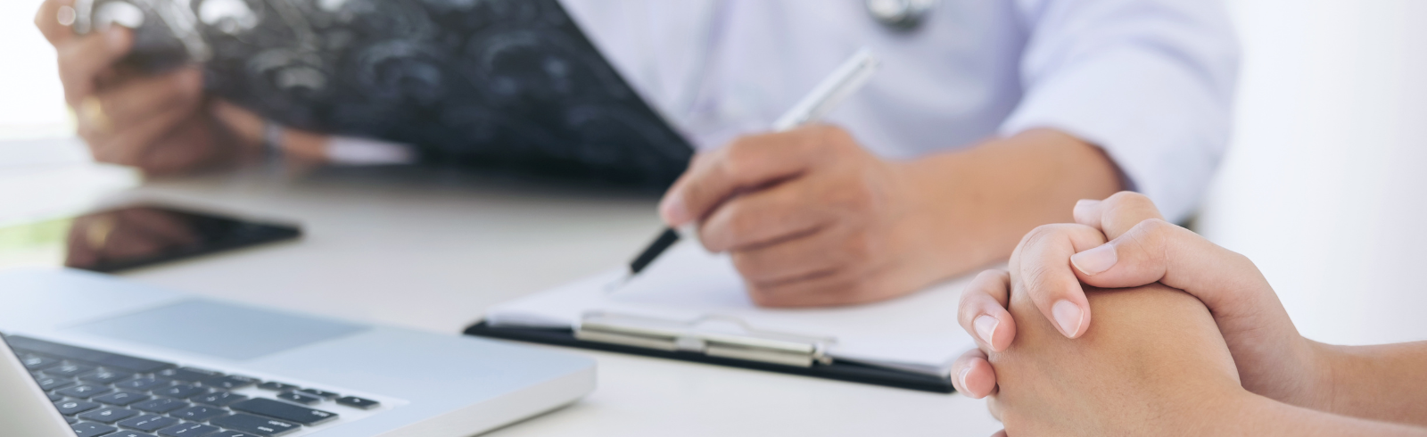 Medical professional with laptop and scans with patient