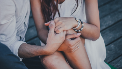 Close up of man and woman's hands hugging knees