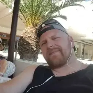 Man in baseball cap, earphones in smiling at the camera