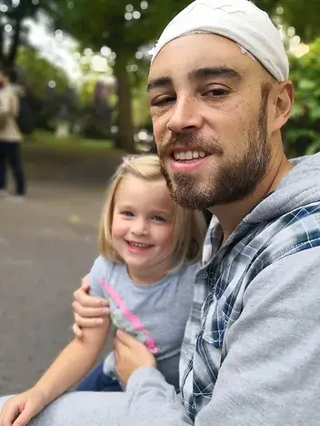 Smiling bearded young man holding is little daughter
