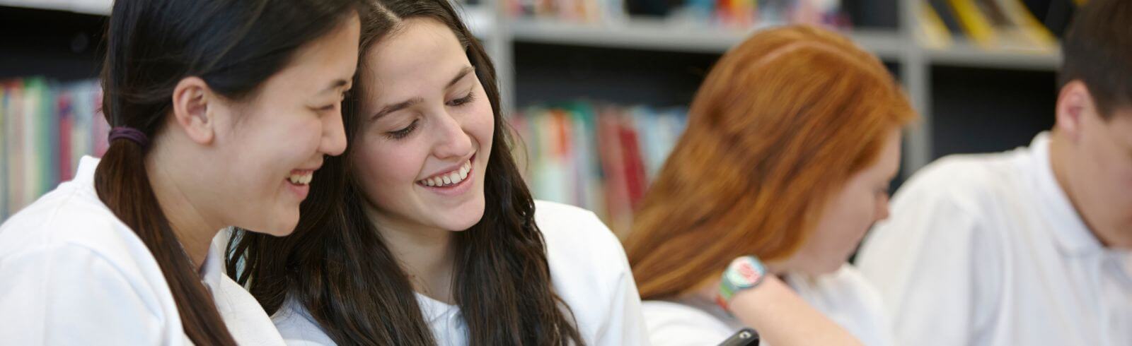 Schoolgirls in classroom chatting to each other