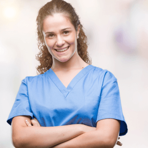 Young nurse in blue scrubs and arms crossed smiling