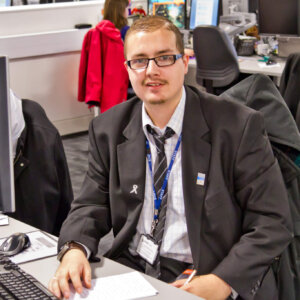 Young man in suit and tie sitting at office desk