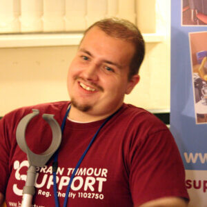 Young man smiling, wearing Brain Tumour Support t-shirt
