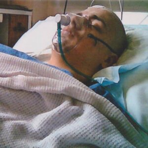 Young man unconscious in hospital bed with oxygen mask on