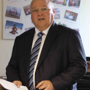 Man wearing suit and tie, giving a speech