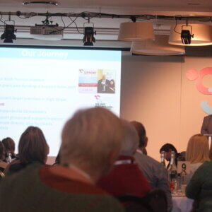 Man standing next to display screen addressing a conference
