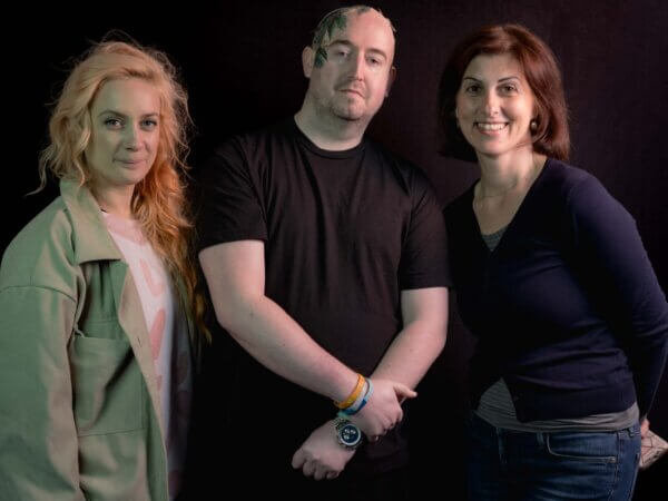 Man and two women standing against black background