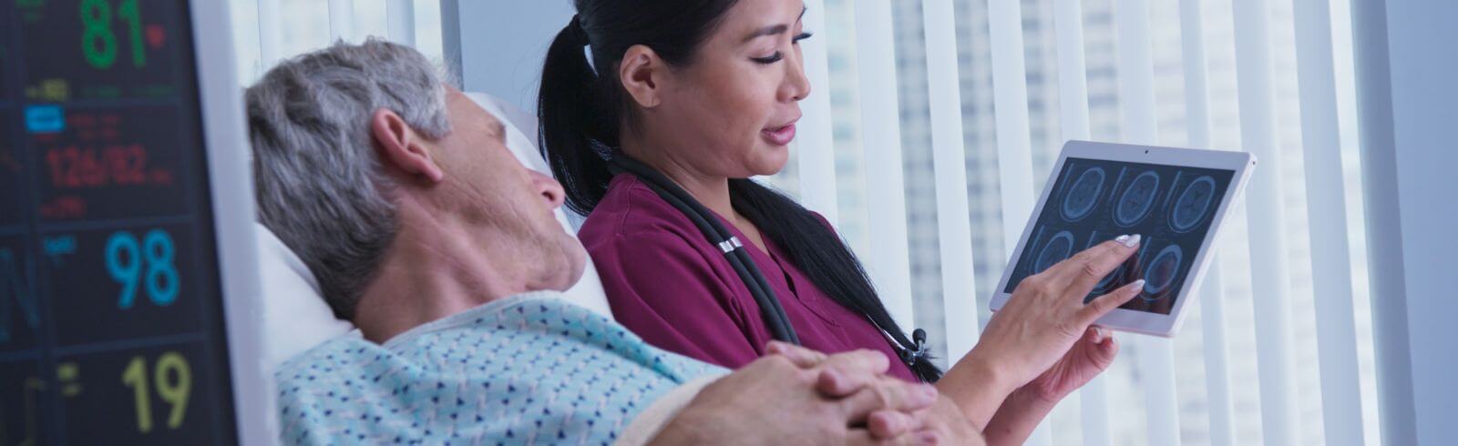 Image shows a young female doctor discussing brain scan results with hospital patient