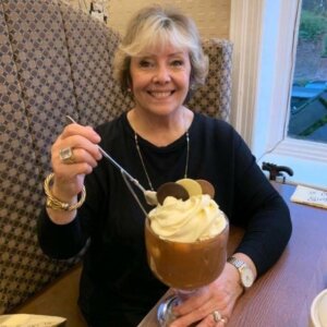 Vibrant, smiling elderly lady eating a large chocolate dessert