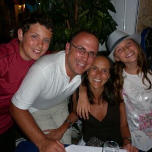 Ben and his lovely family, who want to raise funds for Brain Tumour Support in his honour. Ben, his Dad, Mum and sister all cuddle together smiling. The young family wear summer clothes and look very happy.