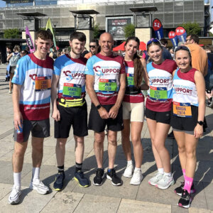 Three men and three women standing together in a line, smiling and wearing Brain Tumour Support running tops