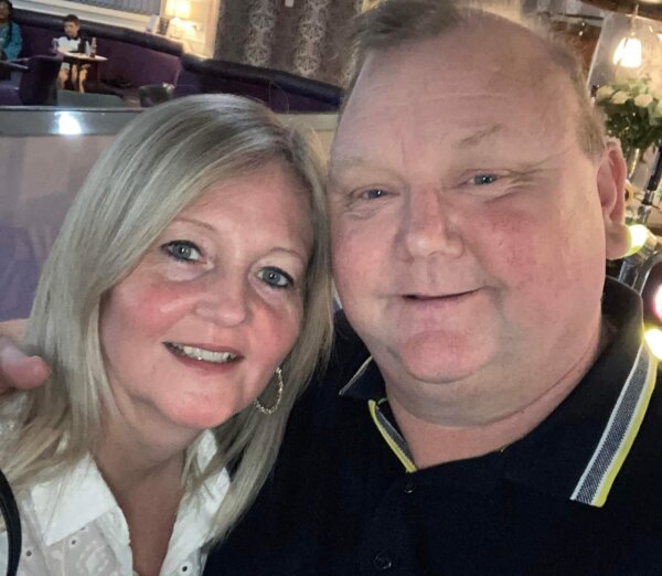 middle aged woman and man with heads together affectionately, smiling towards camera