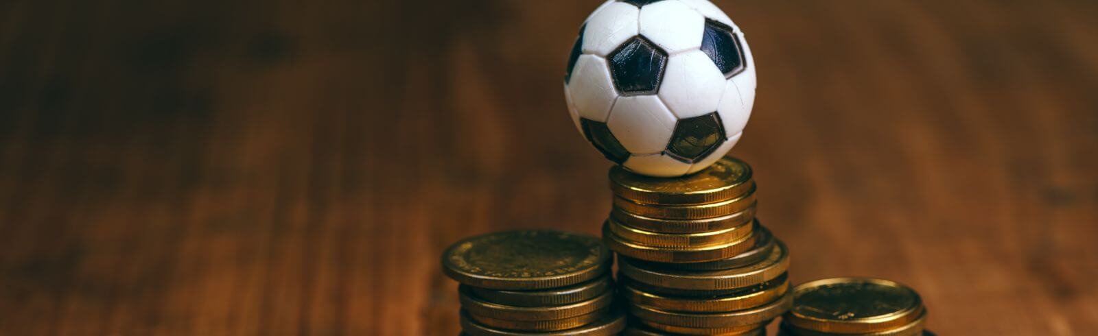 Image shows a small football sitting on top of piles of copper coloured coins