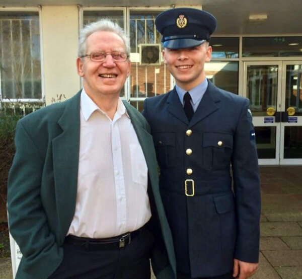 Elderly man standing proudly next to young man in RAF uniform, both smiling