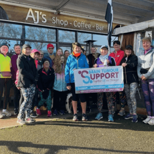Group of supporters from running club holding Brain Tumour Support banner