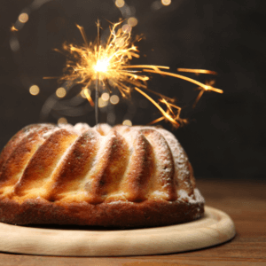 Cake set against a dark backdrop with a sparkler on top