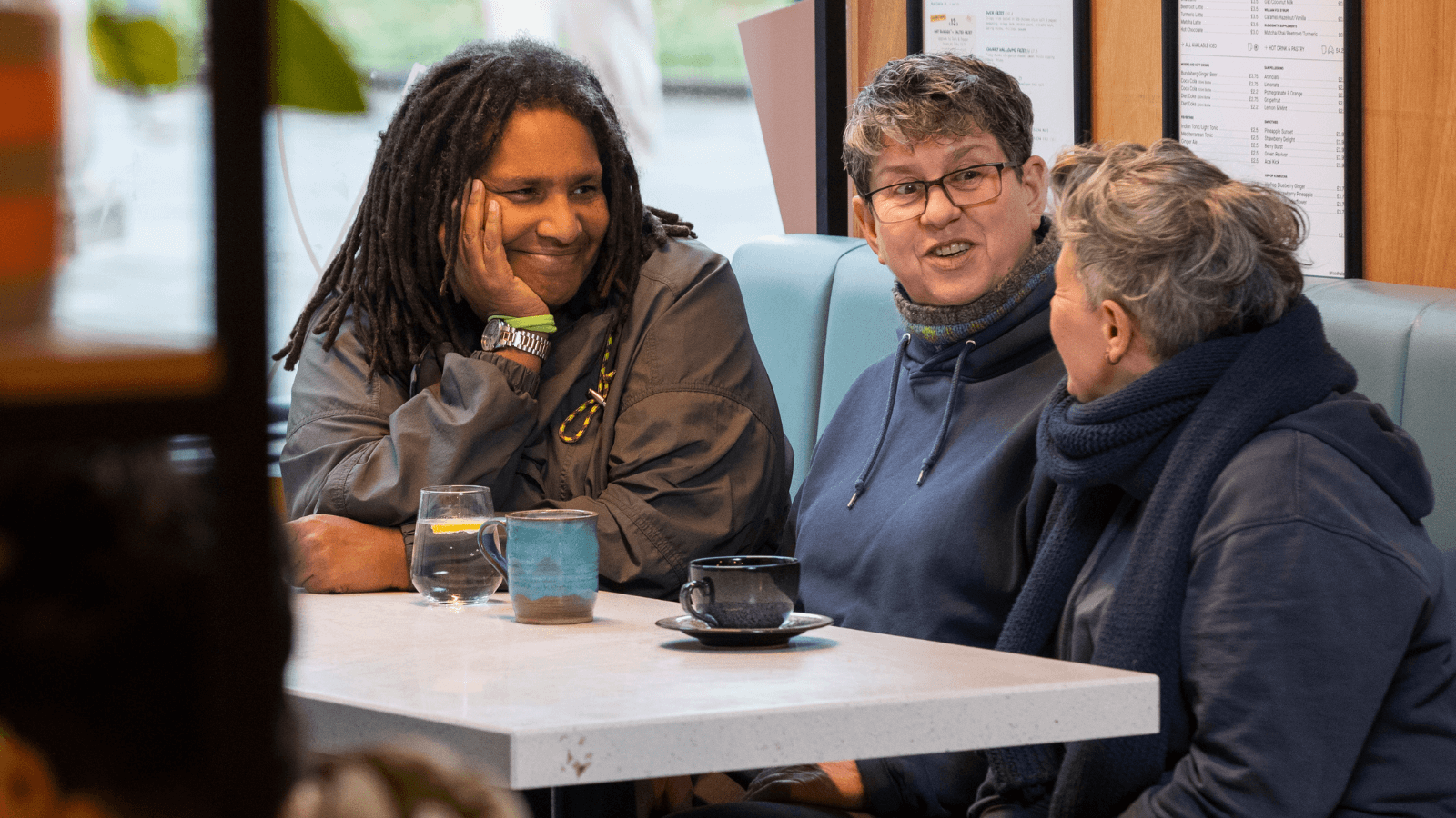 Three people chatting at a table over drinks