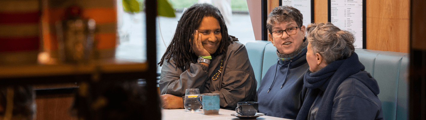 Three people chatting at a table over drinks