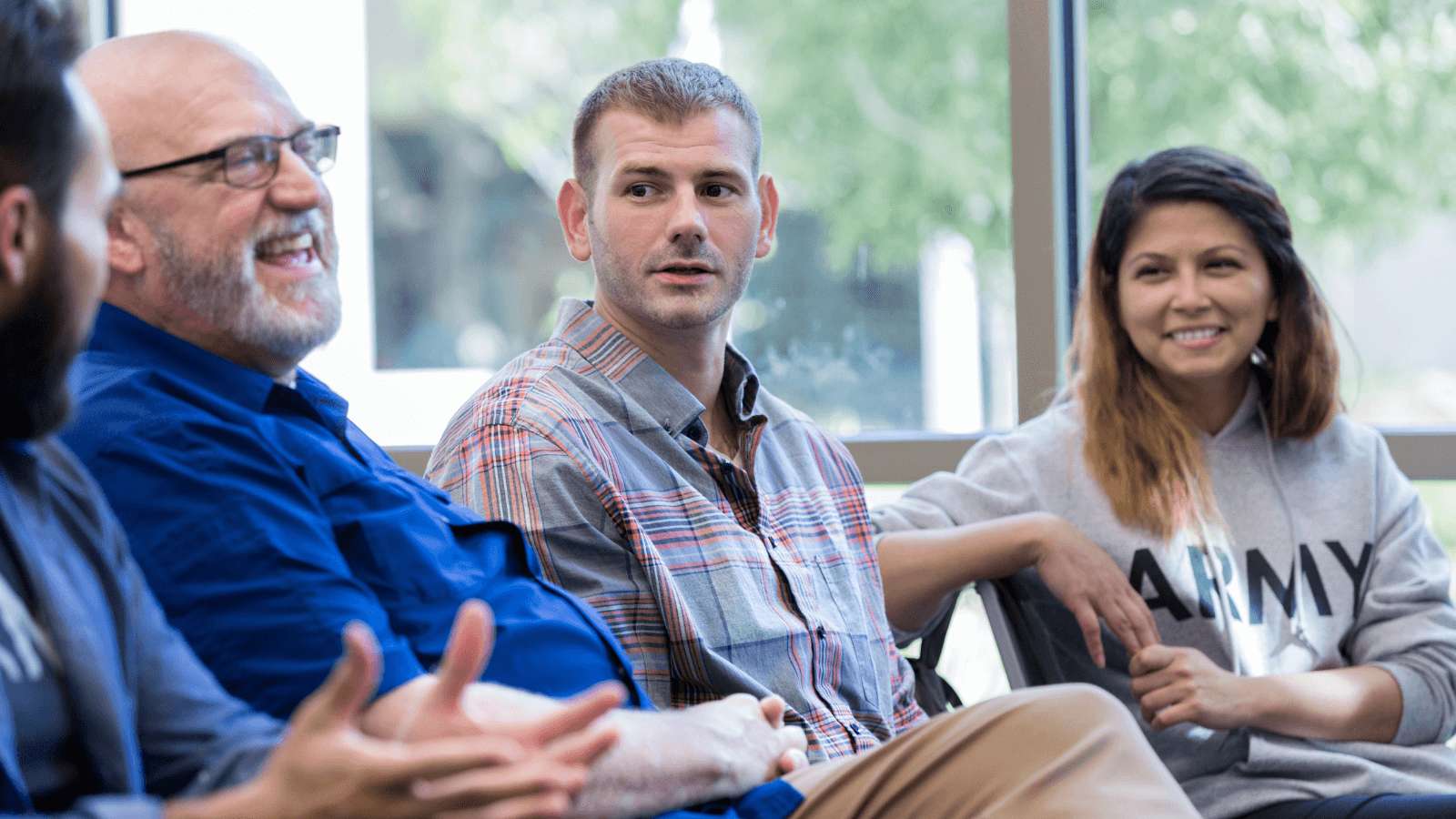 Group interacting -older man with grey beard smiling, younger man and smiling woman looking towards him
