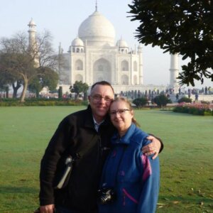 Man and woman, his arm around her shoulder, with the Taj Mahal in the background