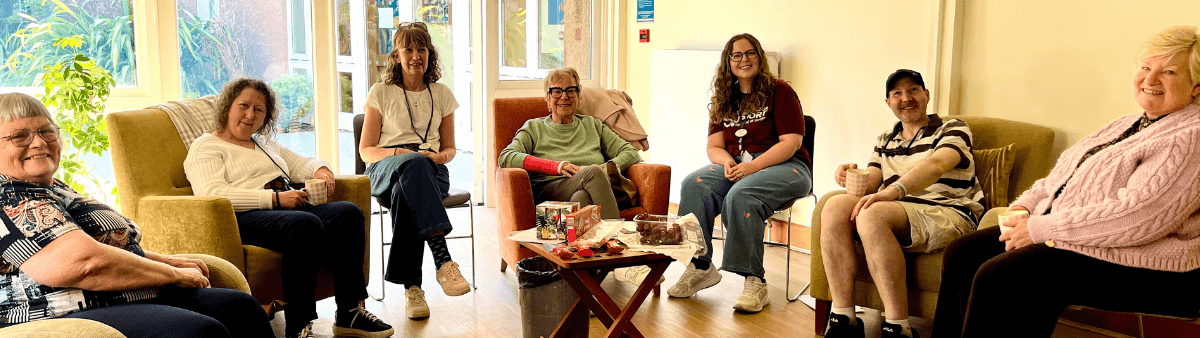Group of people sitting, relaxed and smiling, in a sunny room