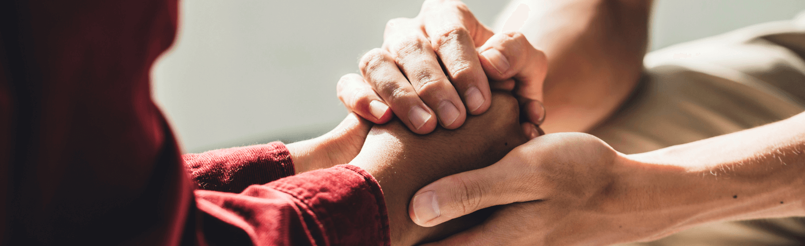 Two pairs of hands, one wrapped around the other supportively