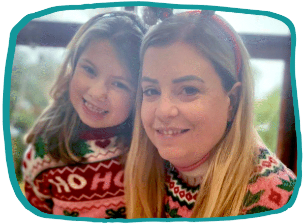 Illustration-style image of Jane and her daughter Alice wearing Christmas jumpers and festive headbands, smiling together at the camera inside an irregular teal frame.