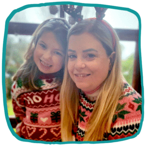 Illustration-style image of Jane and her daughter Alice wearing Christmas jumpers and festive headbands, smiling together at the camera inside an irregular teal frame.