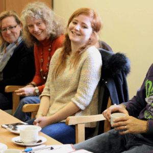 People of varying ages sitting around a table and chatting, friendly and smiling