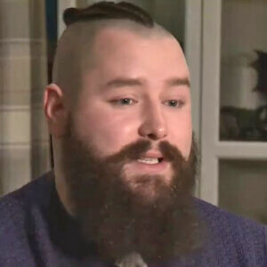 Face of a young man with shaved head and full, thick beard