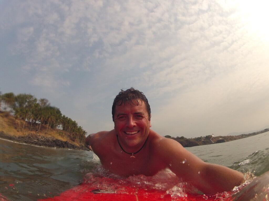 Robert smiling on his surfboard