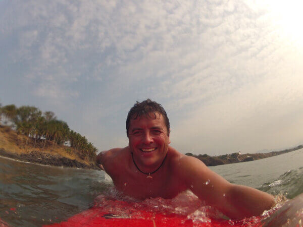 Robert smiling on his surfboard