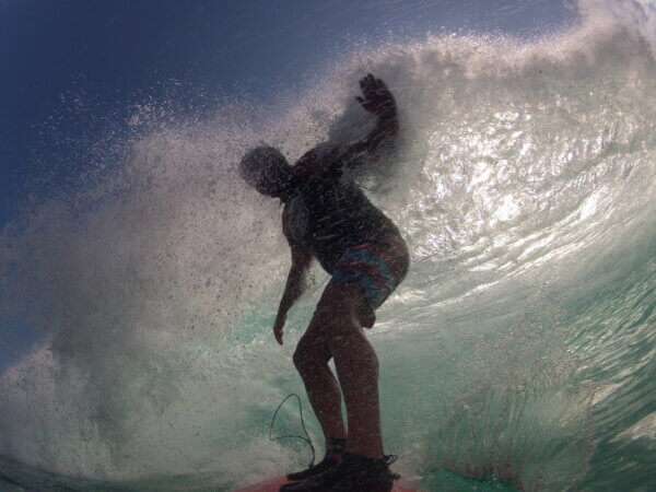 Robert surfing through a breaking wave with water spraying around him