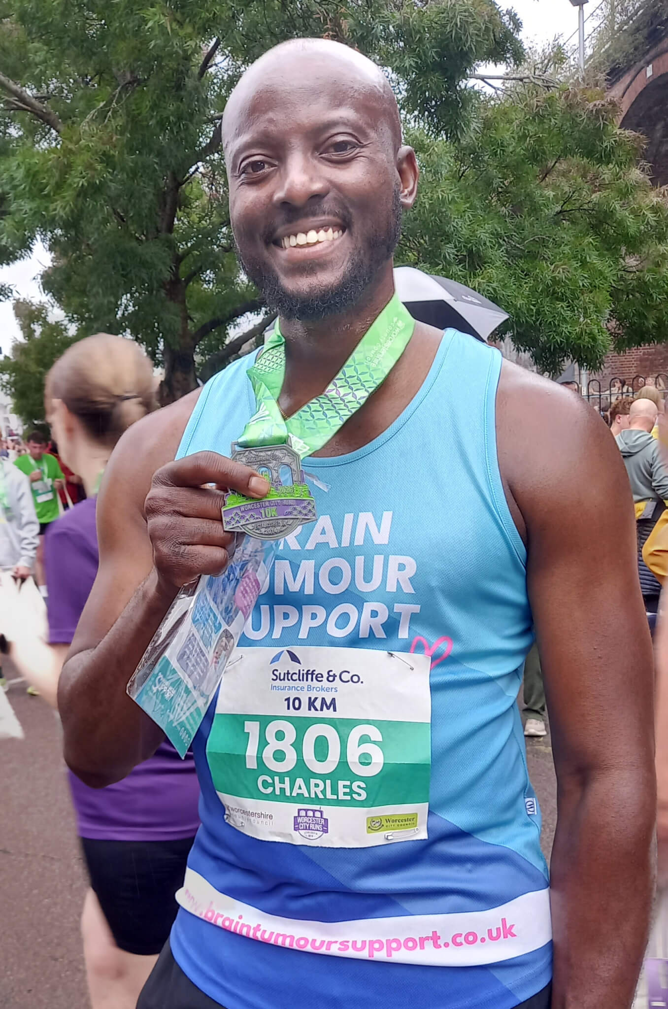 Charles smiling and holding his finishers medal after completing the Worcester City Runs 10K