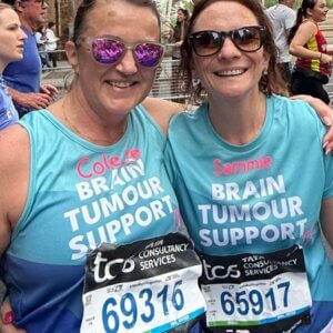Two Brain Tumour Support runners smiling at the camera during the 2026 London Marathon, wearing Brain Tumour Support T-shirts.